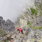 Kobieta schodzi po skałach w dół, w Tatrach na Orlej Perci