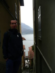 Mężczyzna w ąskiej uliczce w Varennie, w tle jezioro Como
